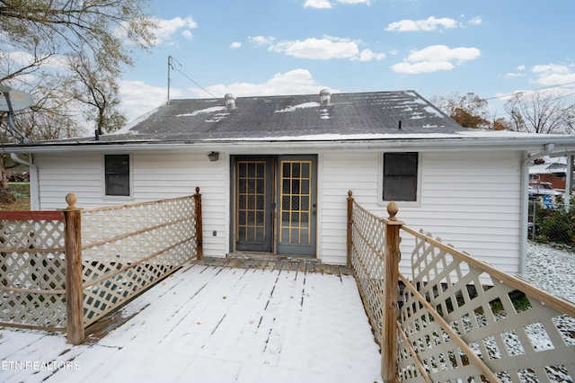 snow covered rear of property featuring a wooden deck and french doors