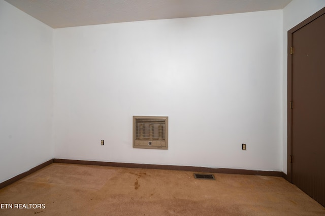 unfurnished room featuring heating unit and carpet floors