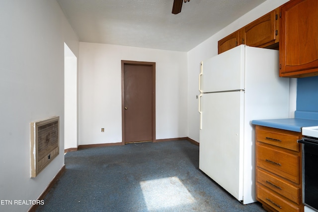 kitchen featuring heating unit, ceiling fan, white fridge, and black range oven