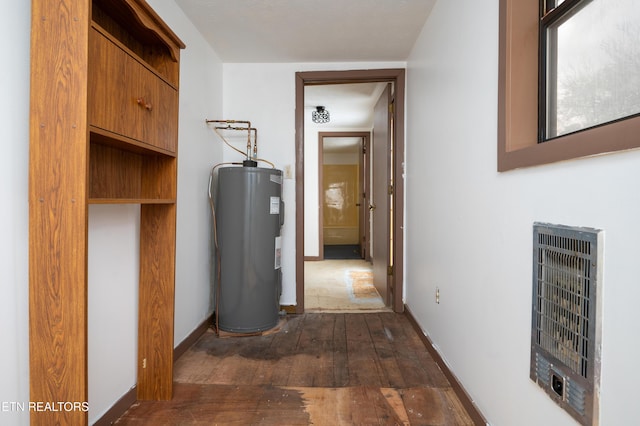 corridor with dark hardwood / wood-style floors, electric water heater, and heating unit