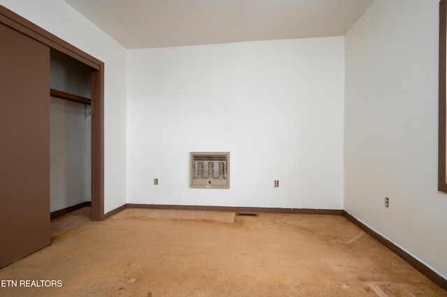 unfurnished bedroom with a closet, light carpet, and heating unit