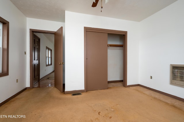 unfurnished bedroom featuring carpet flooring, ceiling fan, heating unit, a textured ceiling, and a closet