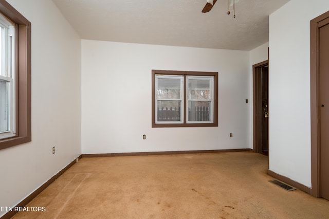 empty room with plenty of natural light, ceiling fan, and light colored carpet