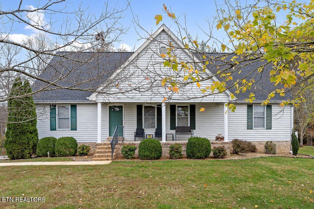 view of front of house featuring a porch, a shingled roof, and a front lawn