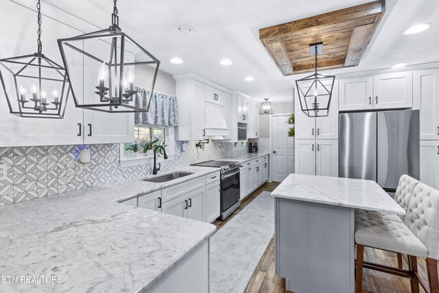 kitchen featuring sink, dark wood-type flooring, decorative light fixtures, white cabinets, and appliances with stainless steel finishes