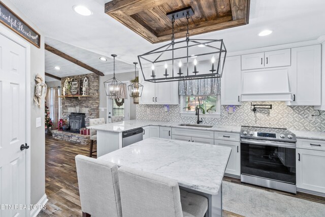 kitchen with a breakfast bar, stainless steel appliances, sink, white cabinets, and dark hardwood / wood-style floors