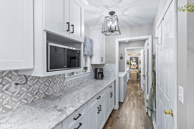 kitchen with white cabinetry, hanging light fixtures, washing machine and dryer, dark hardwood / wood-style floors, and backsplash