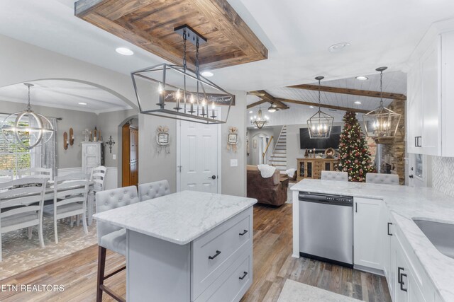 kitchen with stainless steel dishwasher, hardwood / wood-style floors, decorative light fixtures, a breakfast bar, and white cabinets