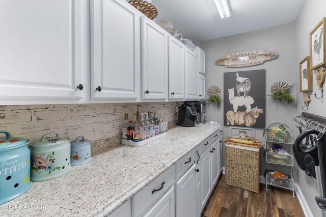 interior space with white cabinets, dark hardwood / wood-style flooring, light stone counters, and tasteful backsplash