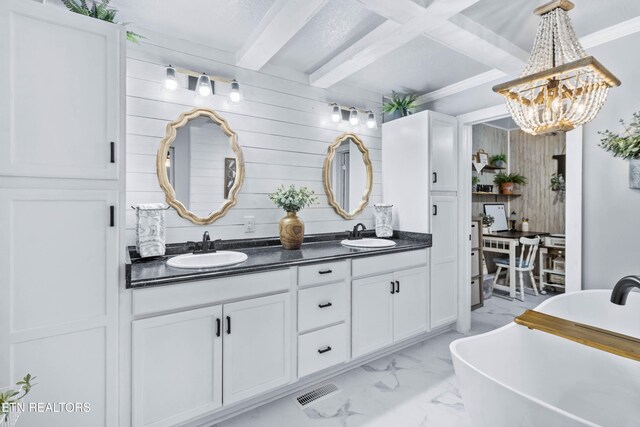 bathroom with a bath, beam ceiling, vanity, and wood walls