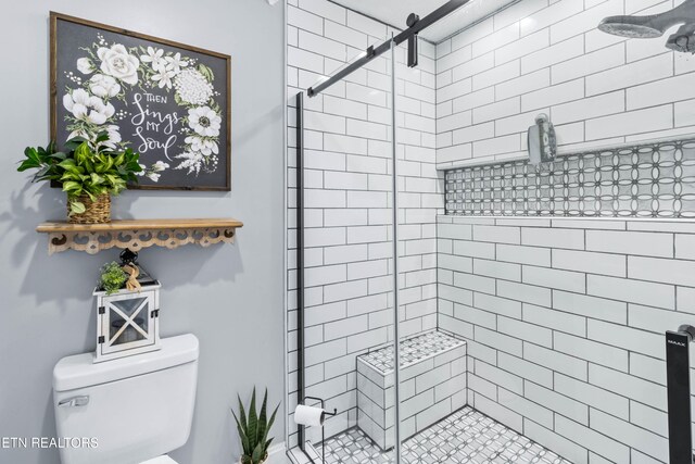 bathroom featuring a shower with door and toilet