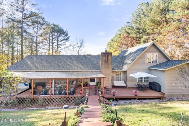 back of property with a lawn, a sunroom, and a wooden deck