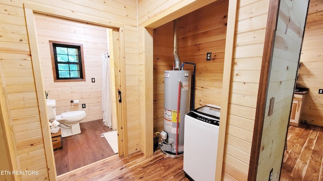 interior space with gas water heater, hardwood / wood-style flooring, and wooden walls