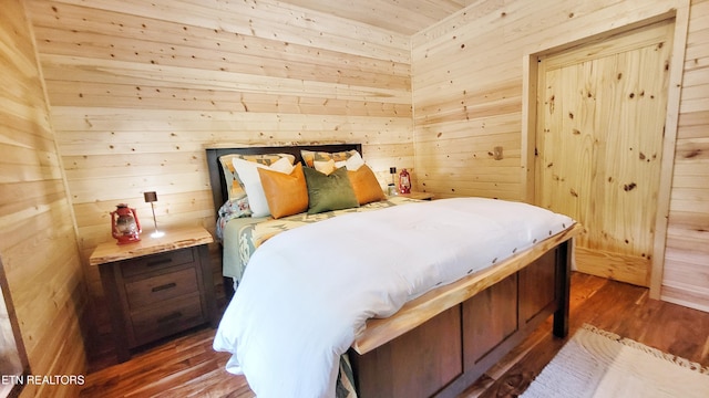 bedroom featuring dark hardwood / wood-style flooring and wooden walls