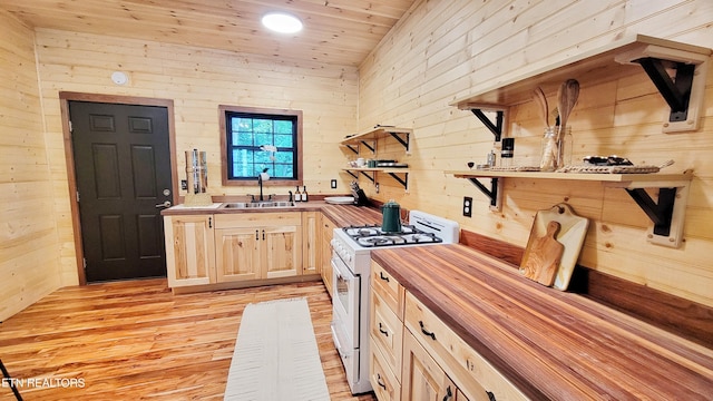 kitchen with wood counters, wood walls, sink, light hardwood / wood-style flooring, and white range oven