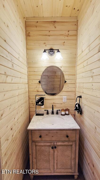 bathroom with wood walls, vanity, and wooden ceiling