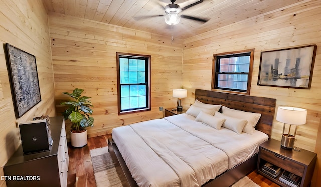 bedroom with wood walls, hardwood / wood-style floors, ceiling fan, and wood ceiling