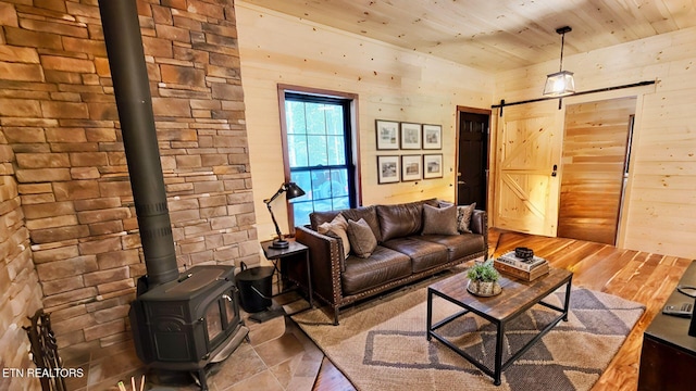 living room with wood-type flooring, a barn door, a wood stove, and wooden ceiling