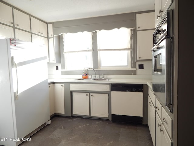 kitchen featuring white appliances, white cabinetry, and sink