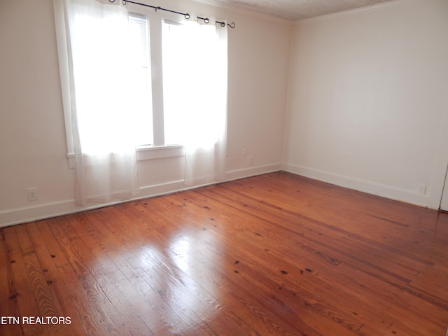 spare room featuring hardwood / wood-style flooring, ornamental molding, a textured ceiling, and a wealth of natural light