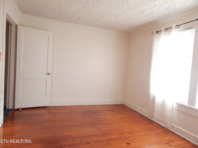 unfurnished room featuring a textured ceiling, hardwood / wood-style flooring, and crown molding