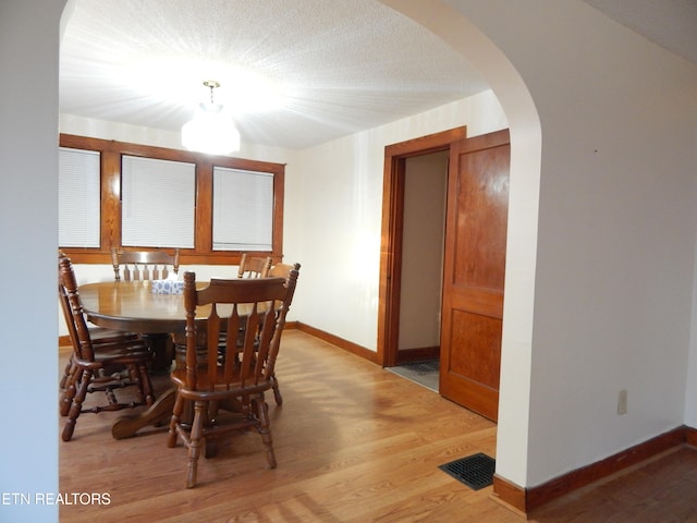 dining area with light hardwood / wood-style flooring and a textured ceiling