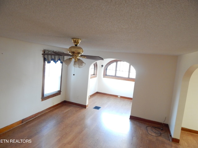 unfurnished room with ceiling fan, a textured ceiling, and light hardwood / wood-style flooring