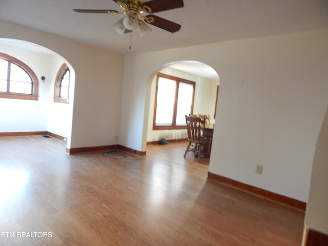 empty room with hardwood / wood-style flooring, ceiling fan, and a healthy amount of sunlight