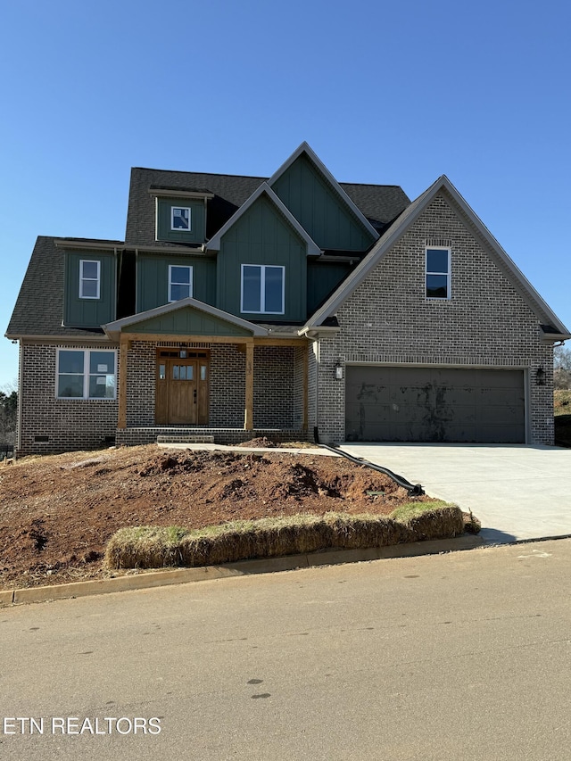 view of front facade with driveway, roof with shingles, an attached garage, board and batten siding, and brick siding