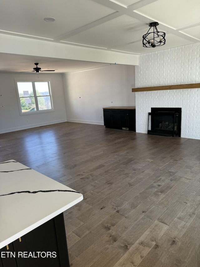 unfurnished living room with dark wood-style floors, a fireplace, a ceiling fan, and baseboards