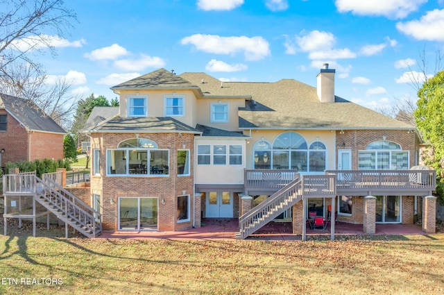 rear view of property with a patio, a lawn, and a wooden deck