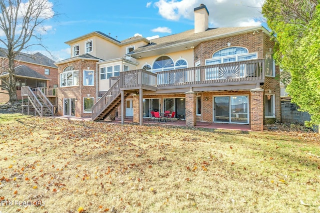 back of property with a lawn, a patio area, and a wooden deck