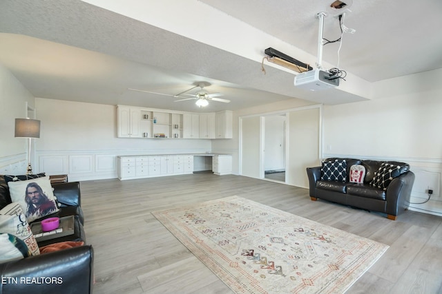 living room with a textured ceiling, light hardwood / wood-style flooring, and ceiling fan