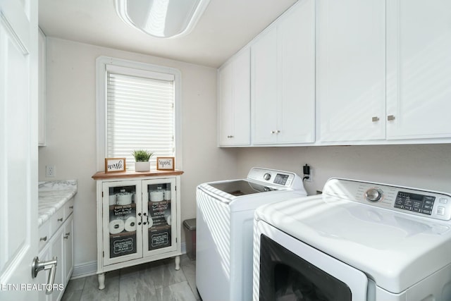 clothes washing area with washing machine and dryer and cabinets