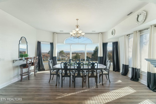 dining room featuring a mountain view, dark hardwood / wood-style flooring, a wealth of natural light, and a chandelier