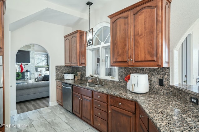 kitchen featuring sink, stainless steel dishwasher, dark stone counters, pendant lighting, and decorative backsplash