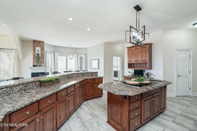 kitchen featuring dark stone counters, sink, decorative light fixtures, black stovetop, and a notable chandelier