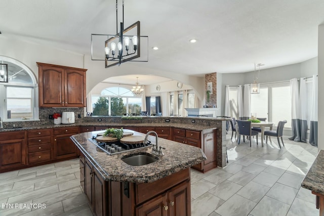 kitchen with backsplash, sink, an island with sink, and decorative light fixtures