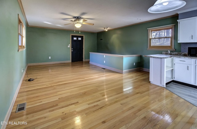 interior space with ceiling fan, crown molding, and light hardwood / wood-style flooring