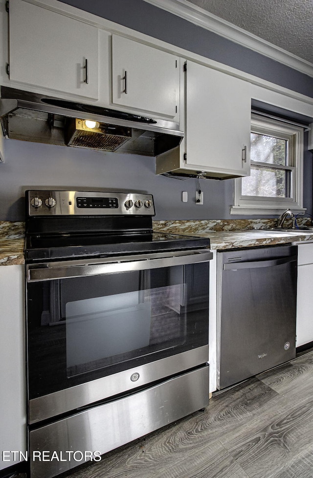 kitchen featuring white cabinetry, crown molding, stainless steel appliances, and hardwood / wood-style flooring