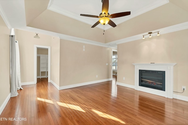 unfurnished living room featuring hardwood / wood-style floors, ceiling fan, crown molding, and a tray ceiling