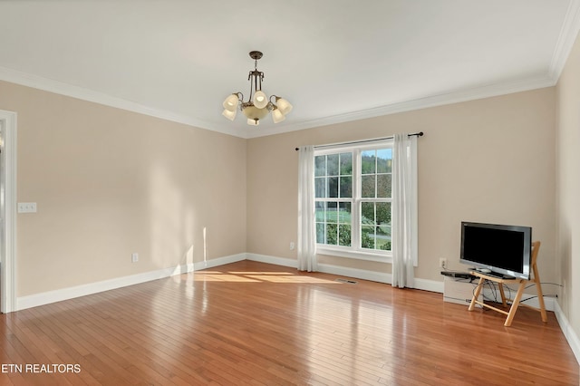 empty room with light wood-type flooring, ornamental molding, and an inviting chandelier