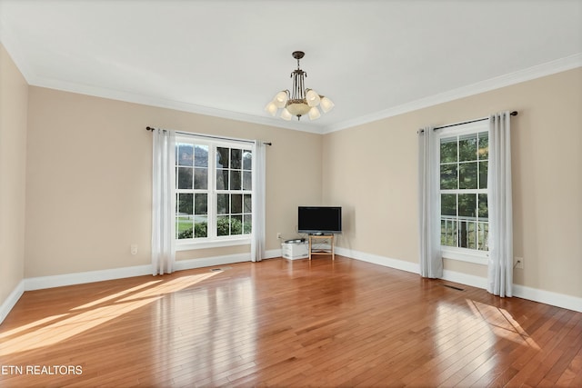 unfurnished living room featuring light wood-type flooring, crown molding, and an inviting chandelier