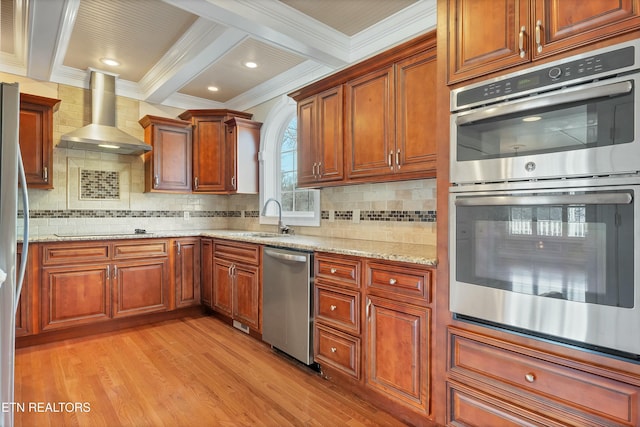 kitchen featuring wall chimney exhaust hood, ornamental molding, appliances with stainless steel finishes, and light hardwood / wood-style flooring