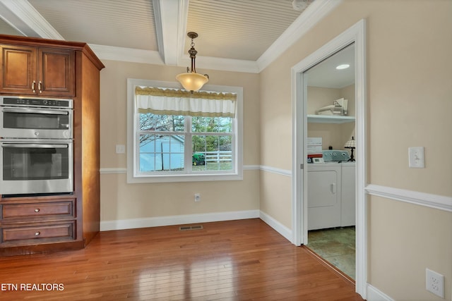 kitchen with washing machine and dryer, double oven, crown molding, decorative light fixtures, and hardwood / wood-style flooring