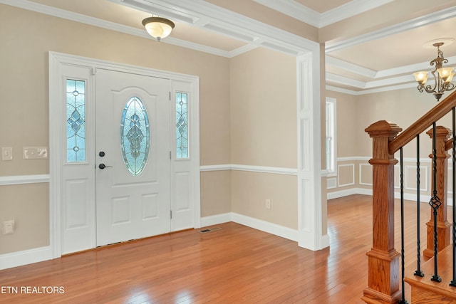 foyer with wood-type flooring, a notable chandelier, and ornamental molding