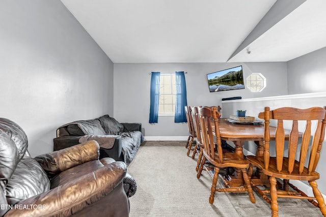 dining area featuring light colored carpet and vaulted ceiling