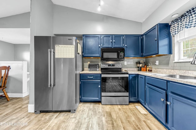 kitchen with blue cabinetry, vaulted ceiling, and appliances with stainless steel finishes