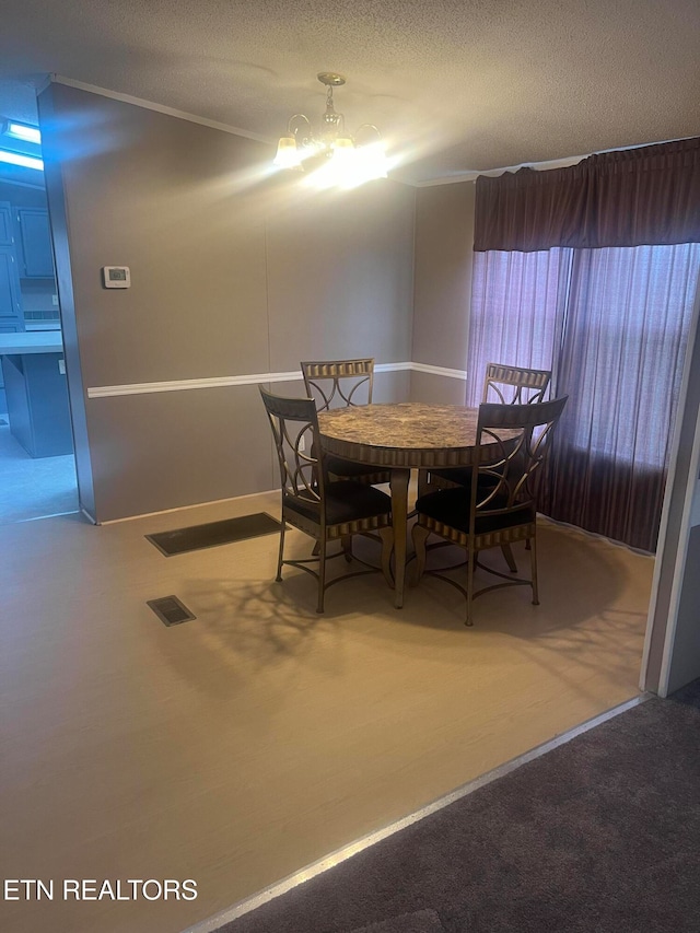 dining area with a notable chandelier, carpet floors, and a textured ceiling