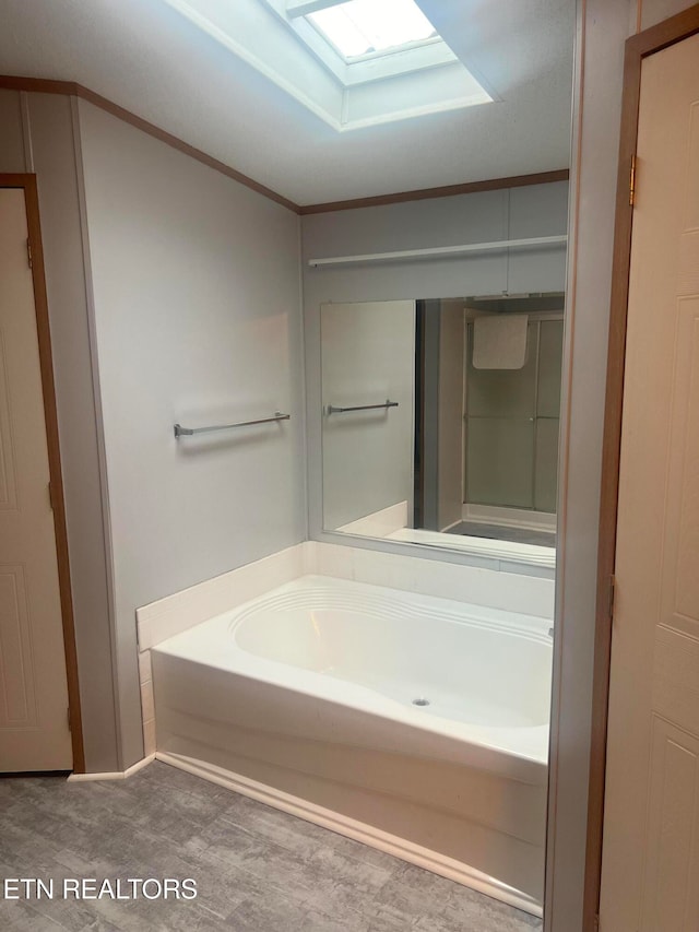 bathroom with ornamental molding, a bath, and a skylight